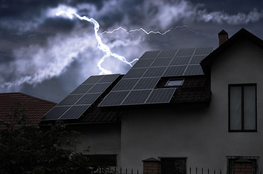 a house with solar panels infront of a cloudy sky and a bolt of lightning in the sky behind it
