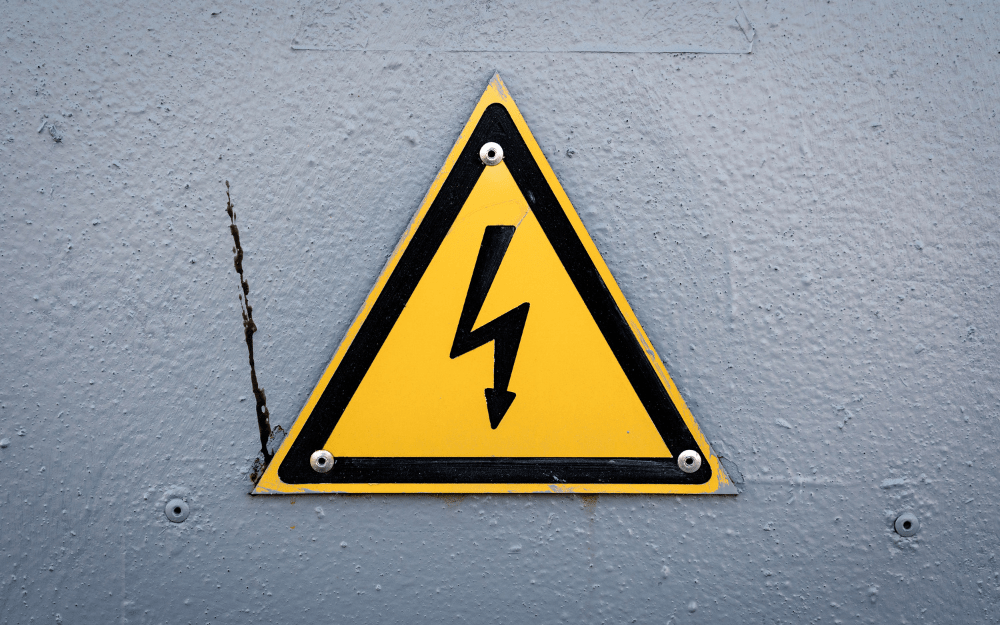 a yellow triangle with black borders with a black lightning bolt arrow pointing downwards